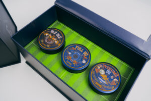 Open Hat Trick box with three glass jars of cannabis flower