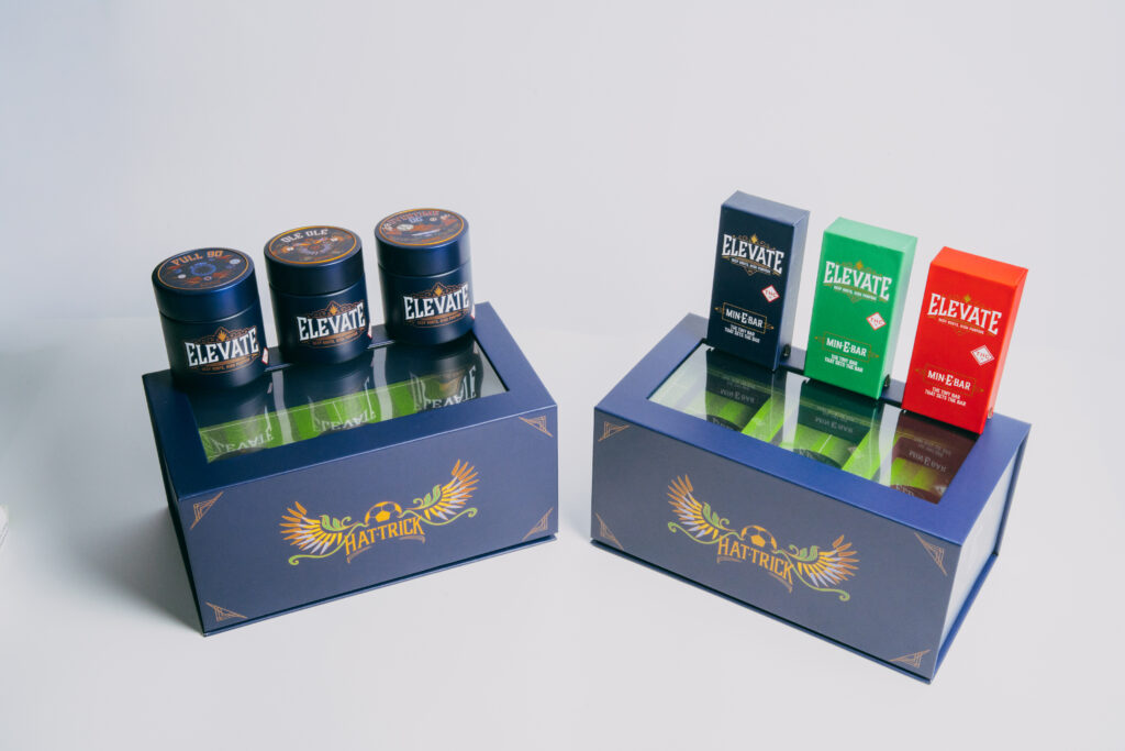 2 navy blue Hat Trick boxes with art and glass flower jars, vapes on top of them