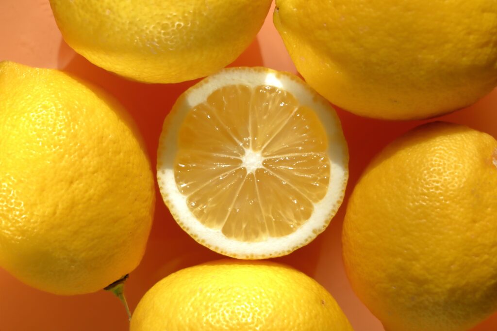 Five whole lemons surrounding a lemon half