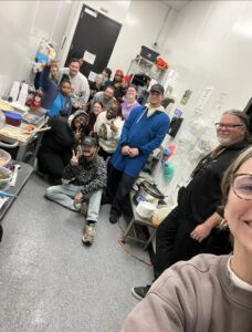 Selfie taken by a woman with people posing and smiling in the background
