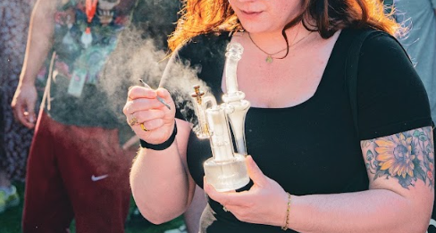 woman in a black tab holding a dab rig at a festival